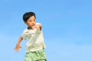 青空の下でダンスを踊る男児