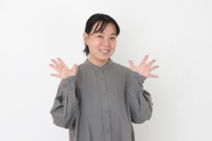 顔の横で笑顔で手を広げる中年女性